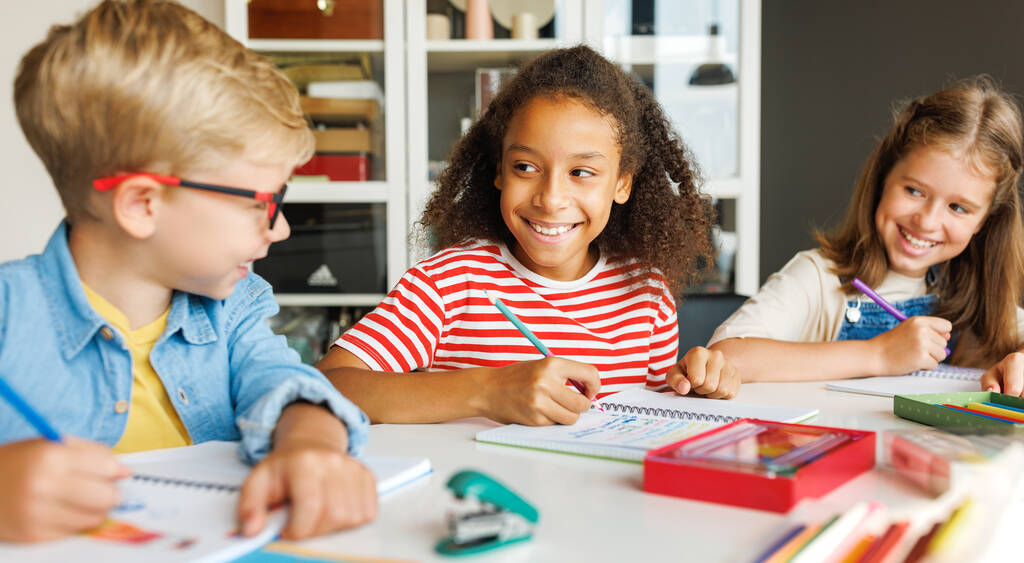 Cheerful ethnic girl solving test with classmates